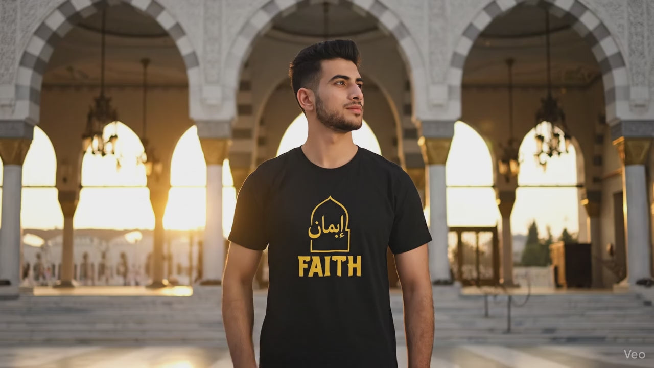 Load video: A Muslim man and woman stand together wearing matching black T-shirts with golden Arabic calligraphy that reads “Iman,” meaning “Faith.” Soft studio lighting. The camera slowly shows the gold design on the front of each shirt, expressing unity, modesty, and modern Islamic streetwear.